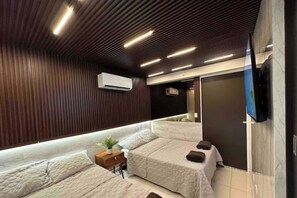 Ein modernes Hotelzimmer mit zwei Betten, einem Fernseher und einer Holzbalkendecke.
