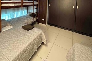 Una habitación con dos literas, un armario y piso de baldosas.