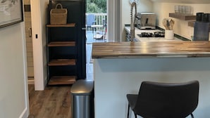 A modern kitchen with a central island, built-in shelves, and a view to an outdoor deck.
