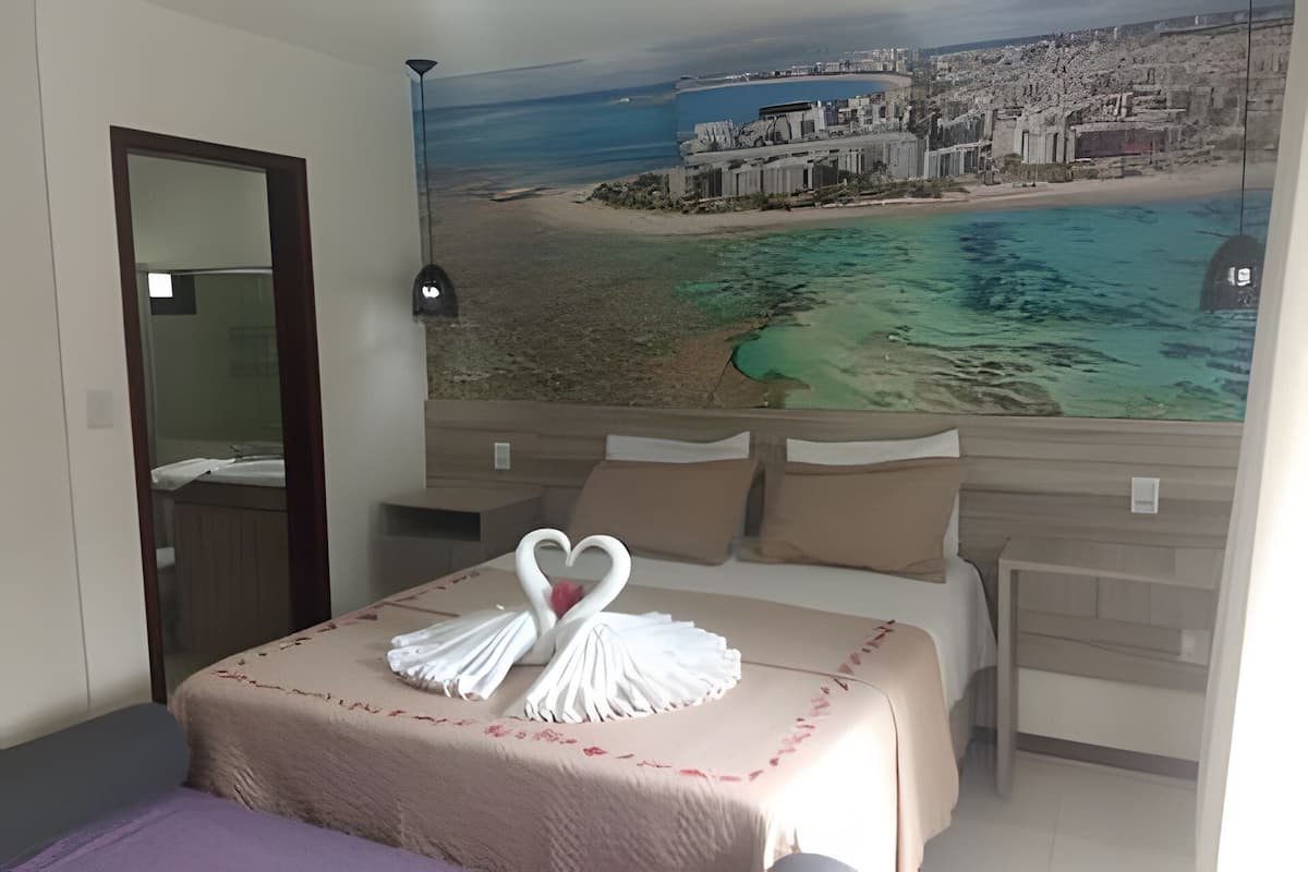 A hotel room with a bed, a large window, and a mural of a beach scene.