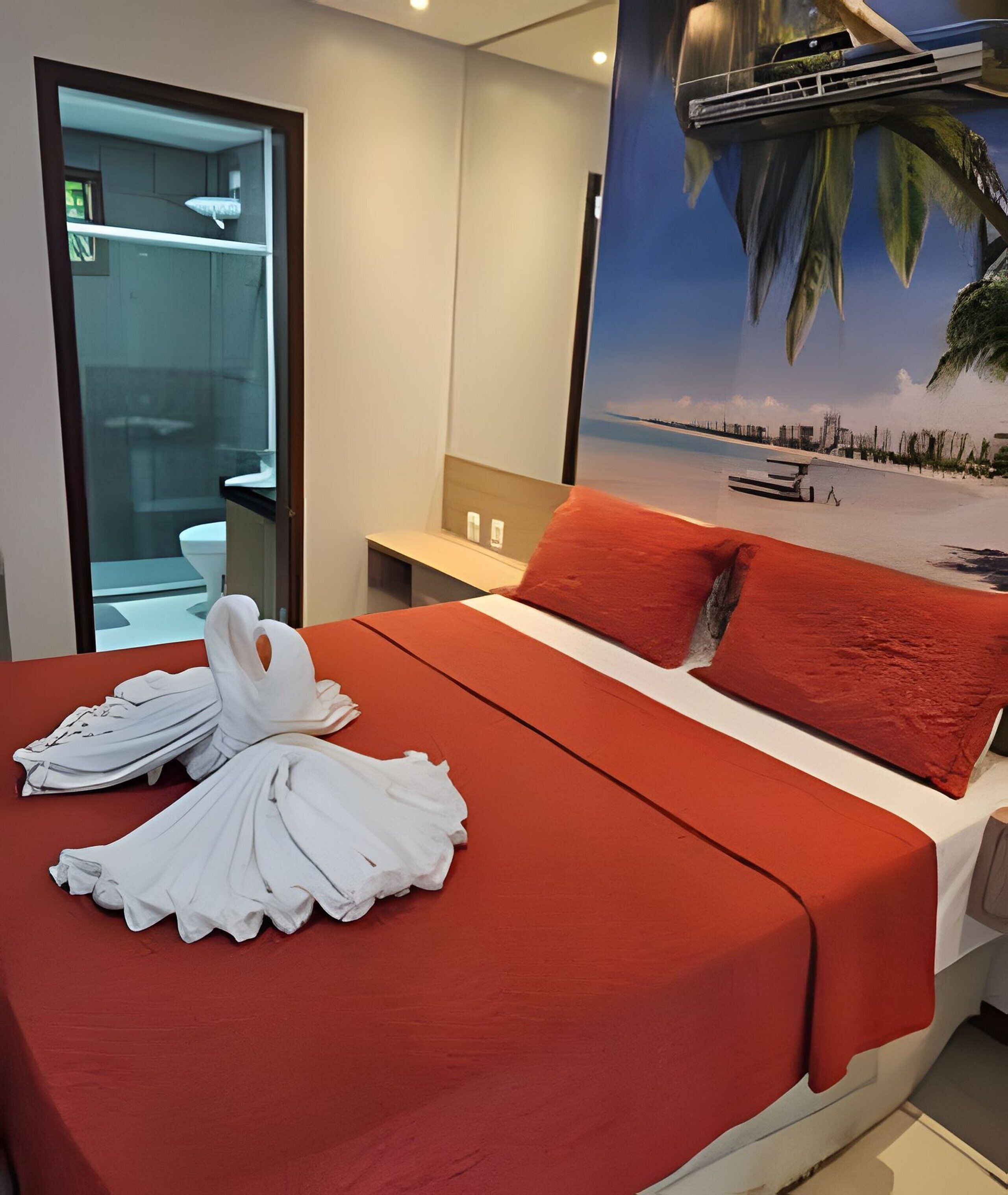 Ett hotellrum med en säng, ett skrivbord och ett badrum som syns genom en glasvägg.