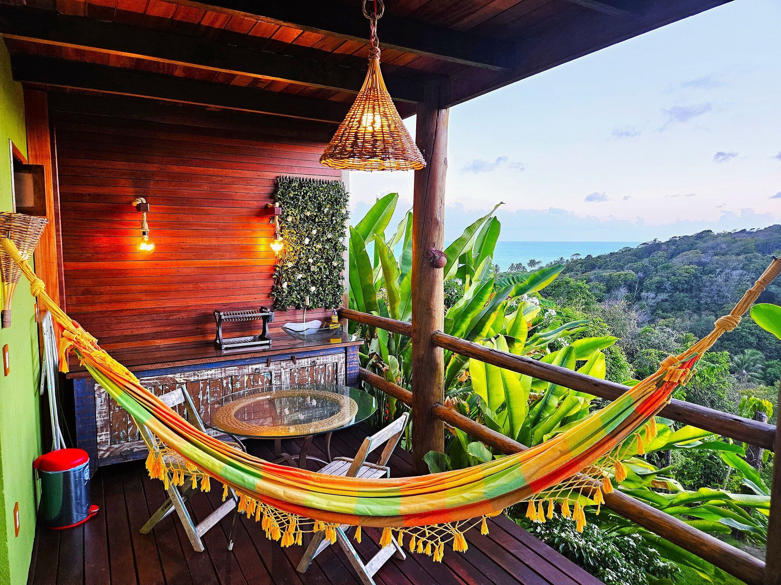 A hammock on a wooden deck with a view of a lush landscape.