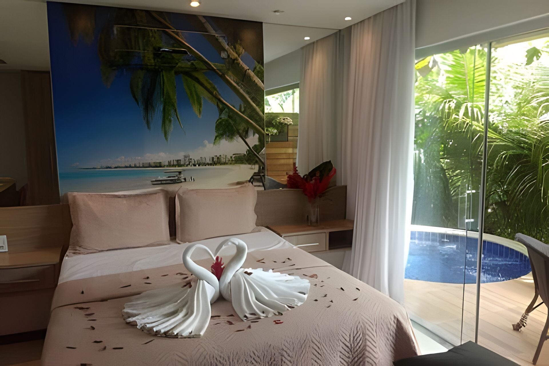 Ett hotellrum med en säng, utsikt över en strand och en balkong med en pool.