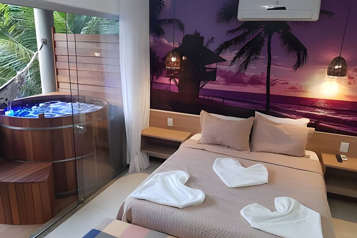 A bedroom with a bed, a hot tub, and a sunset mural.