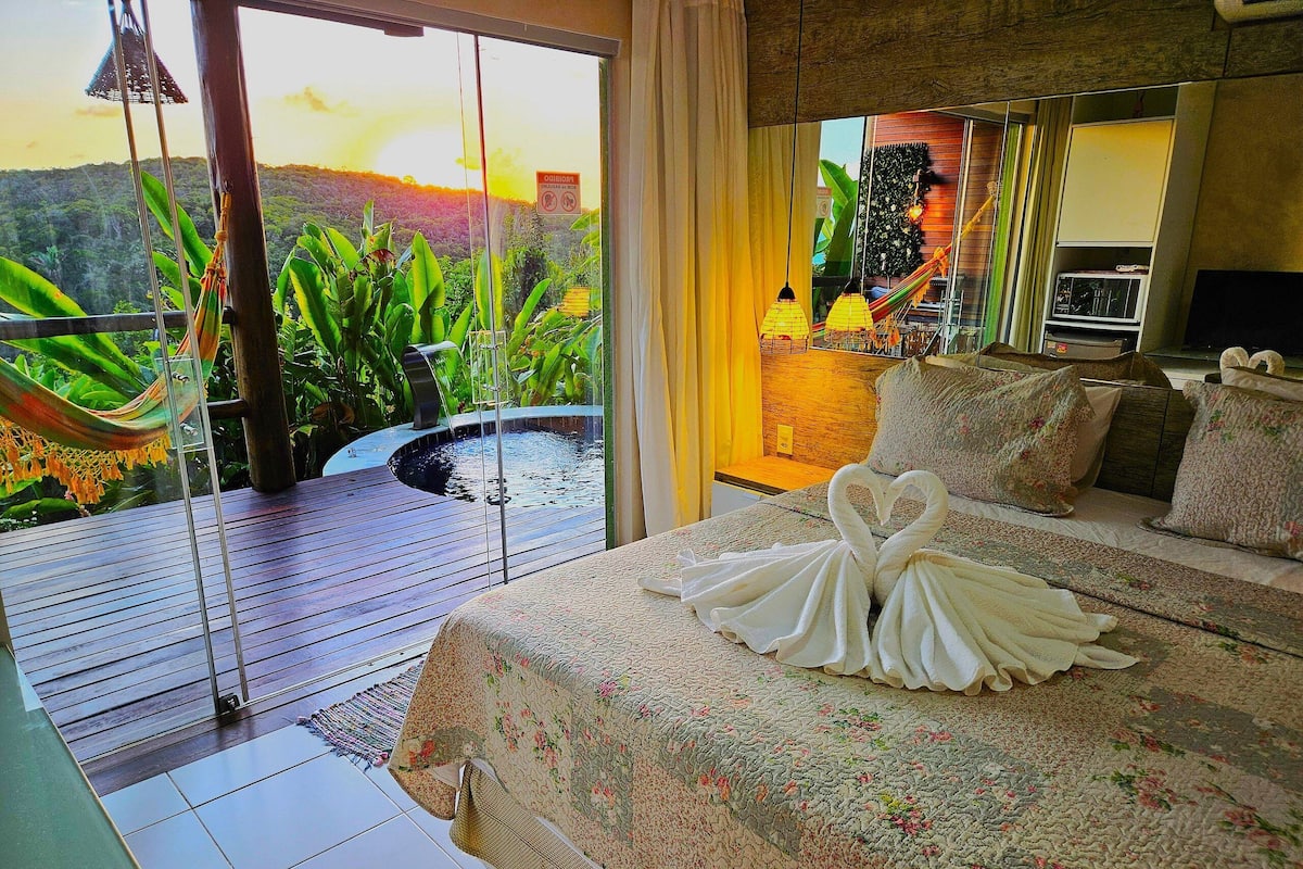 A bedroom with a bed, a view of a waterfall, and a balcony with plants.
