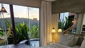 A modern bedroom with a large bed, a view of the outdoors, and a hammock. - Villas do Pratagy (Maceió)