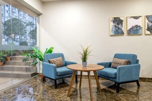 Un vestíbulo con dos sillones azules, una mesita redonda y una planta en maceta.