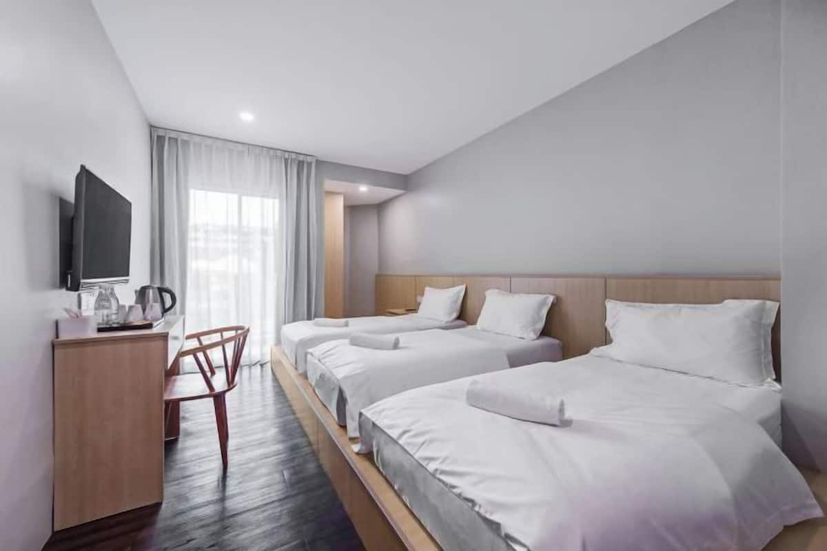 Een hotelkamer met twee bedden, een bureau, een stoel en een televisie.