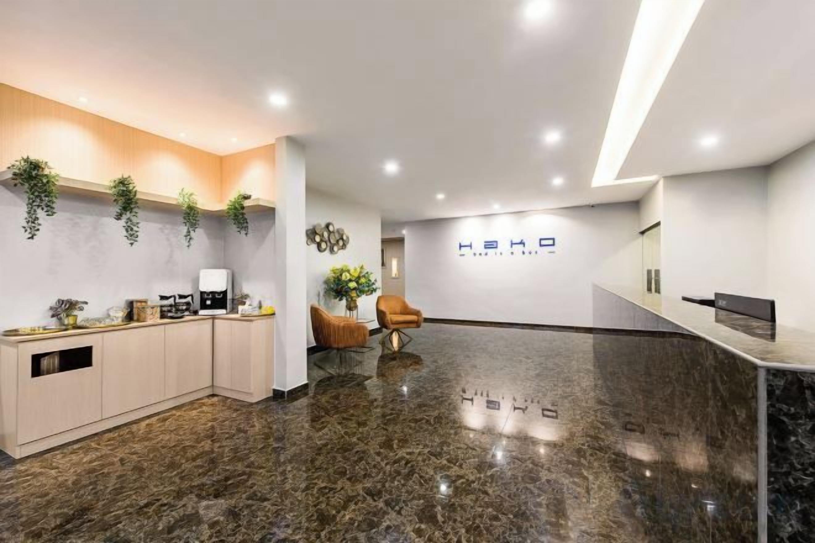 A modern reception area with a marble floor, a reception desk, a seating area with a chair, and a wall-mounted sign.