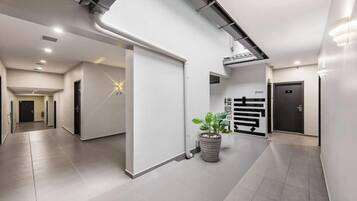 A modern hallway with a potted plant, a star-shaped light fixture, and a door with a sign.