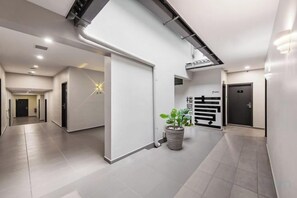 Un pasillo moderno con una planta en maceta, una lámpara con forma de estrella y una puerta con un letrero.