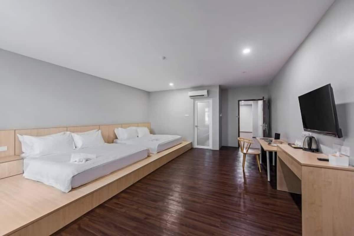 Een hotelkamer met een bed, een bureau, een stoel, een televisie en een airconditioning.