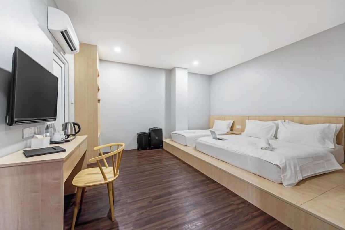 Een hotelkamer met een bed, een bureau, een stoel, een televisie en een airconditioning.