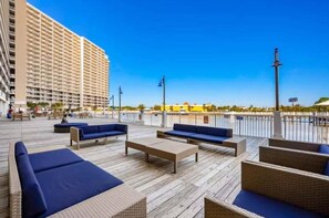 A rooftop deck with outdoor seating, a high-rise building in the background, and a clear sky.