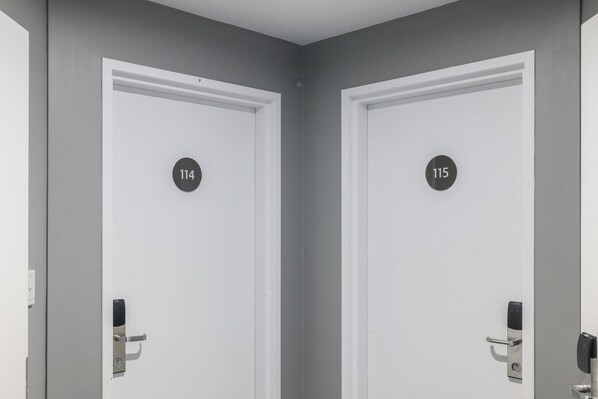 Two white doors with black circular numbers, 114 and 115, indicating room numbers.