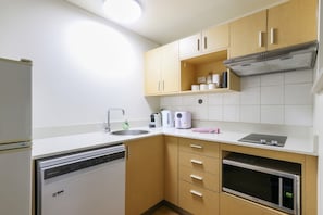 Kompakti keittiö, jossa on astianpesukone, mikroaaltouuni, liesi ja kahvinkeitin.