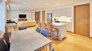 A modern kitchen with a central island, built-in cabinets, and a flat-screen TV mounted on the wall.