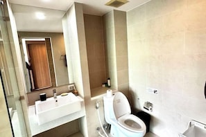 A modern bathroom with a white sink, toilet, and a glass shower enclosure.