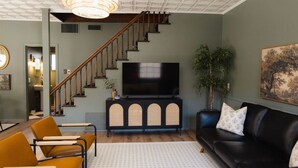 A living room with a staircase, a television, a sofa, and a dining area. - Restored Vintage Carriage House in Mesa (Mesa)