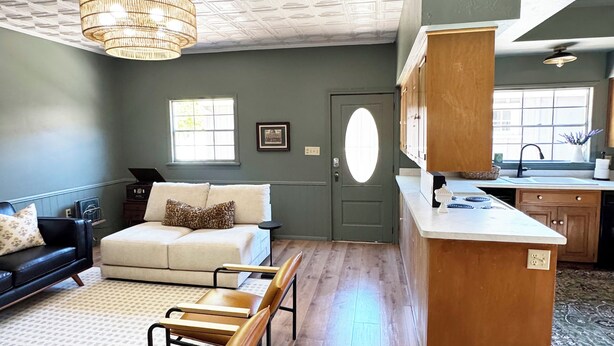 A spacious living area with a sofa, two chairs, a wooden island with a sink, and a kitchen in the background. - Restored Vintage Carriage House in Mesa (Mesa)