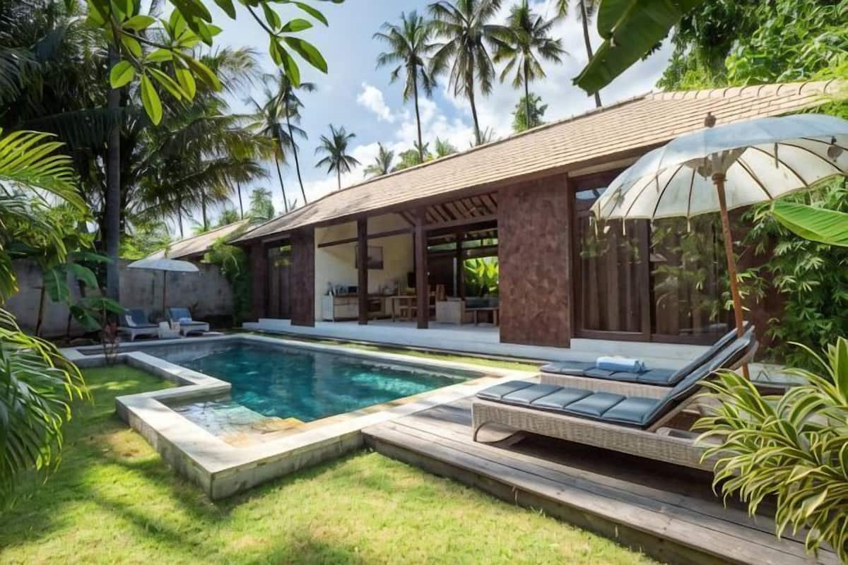 A poolside area with a lounge chair, a covered seating area, and a pool.