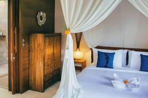 A bedroom with a canopy bed, a wooden wardrobe, and a nightstand with a lamp. - Ruby Romance Oceanside Villa (Bali)