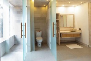 A modern bathroom with a toilet, sink, and mirror. - Ruby Romance Oceanside Villa (Bali)