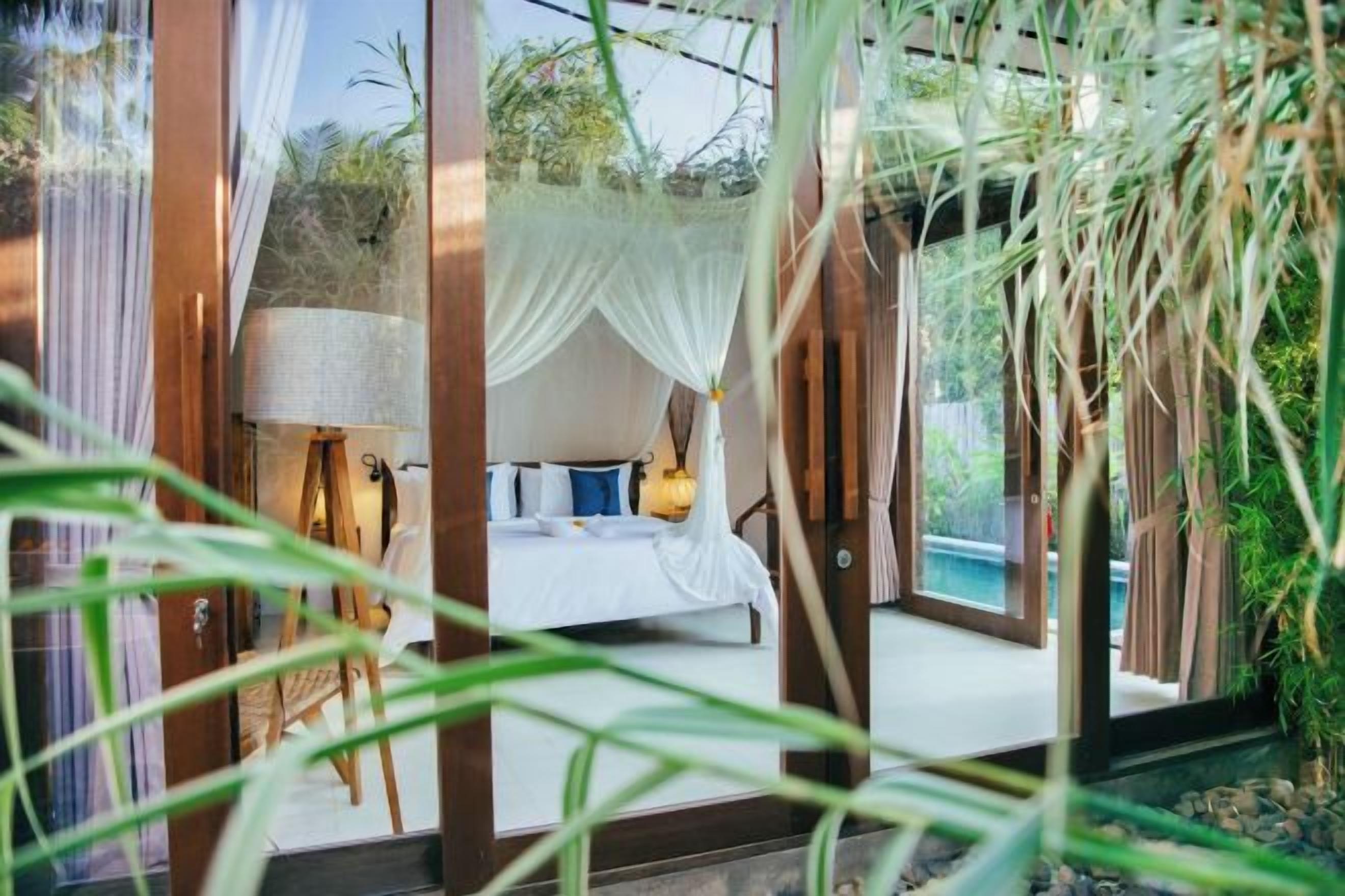 A bedroom with a bed, curtains, and a view of the outdoors.