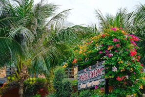 A sign with text, surrounded by lush greenery and flowering plants. - Chomview Lanta Water Park Resort (Koh Lanta)