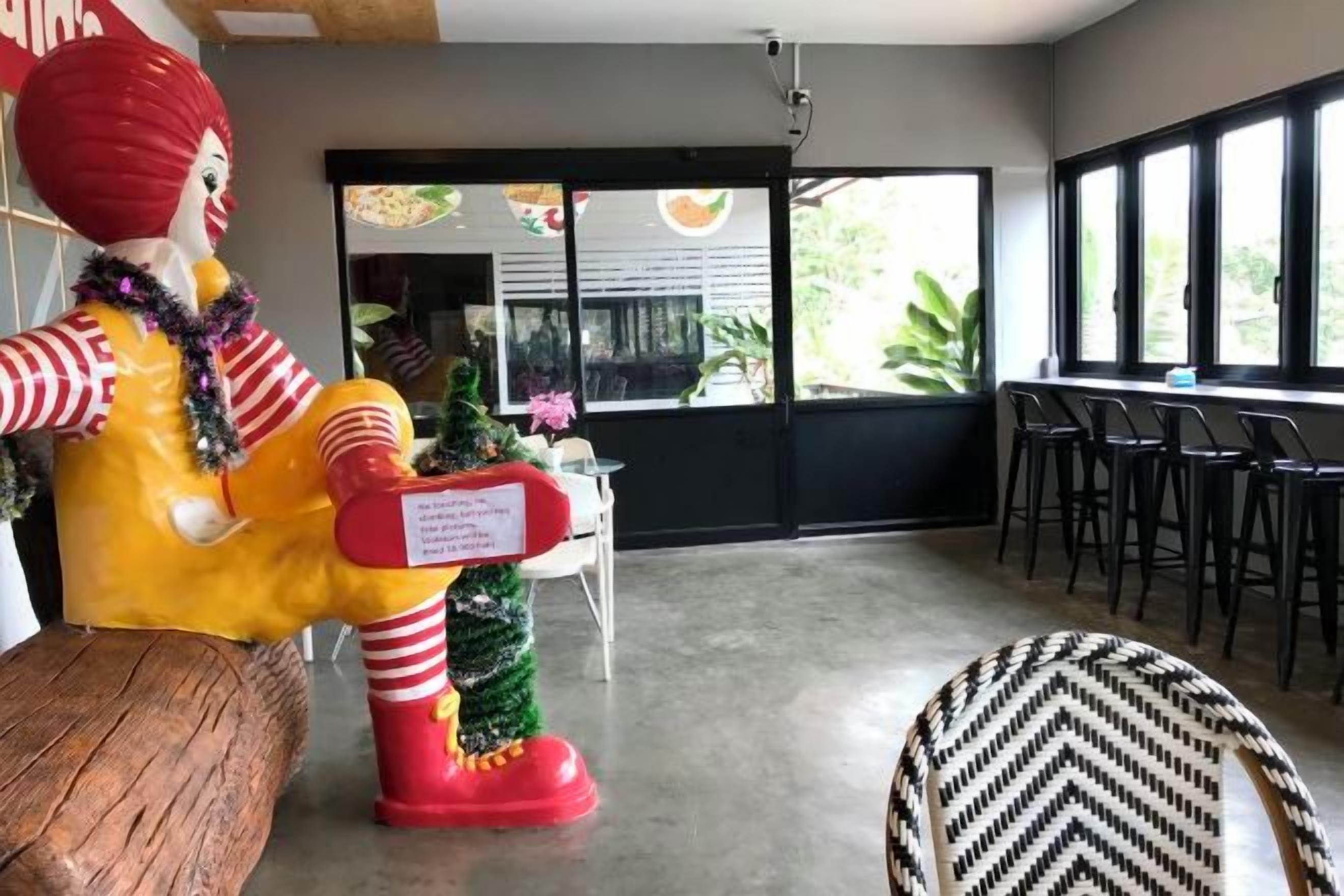 Ein Zimmer mit einer großen Statue, einer kleinen Weihnachtstanne und einer Bar mit Sesseln.
