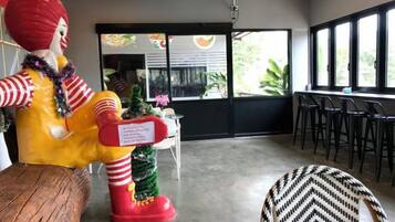 Ein Zimmer mit einer großen Statue, einer kleinen Weihnachtstanne und einer Bar mit Sesseln.