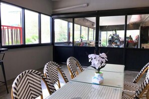 A dining area with a glass table and patterned chairs, large windows, and a view of the outside. - Chomview Lanta Water Park Resort (Koh Lanta)