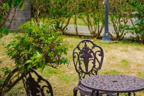 A metal outdoor table and chair set in a garden with grass and bushes. - Chomview Lanta Water Park Resort (Koh Lanta)