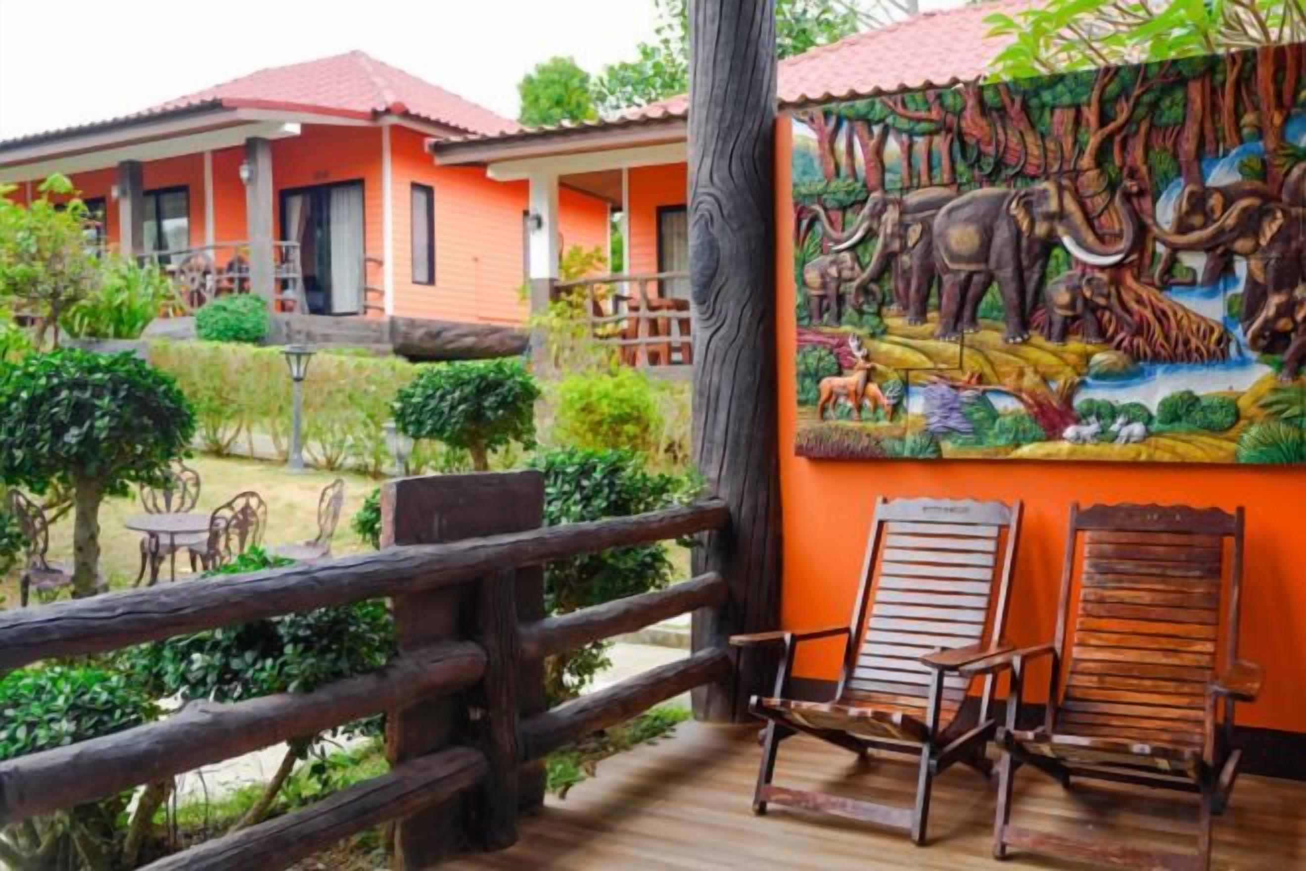 A wooden deck with two chairs, a mural of wildlife, and a building with red roofs.