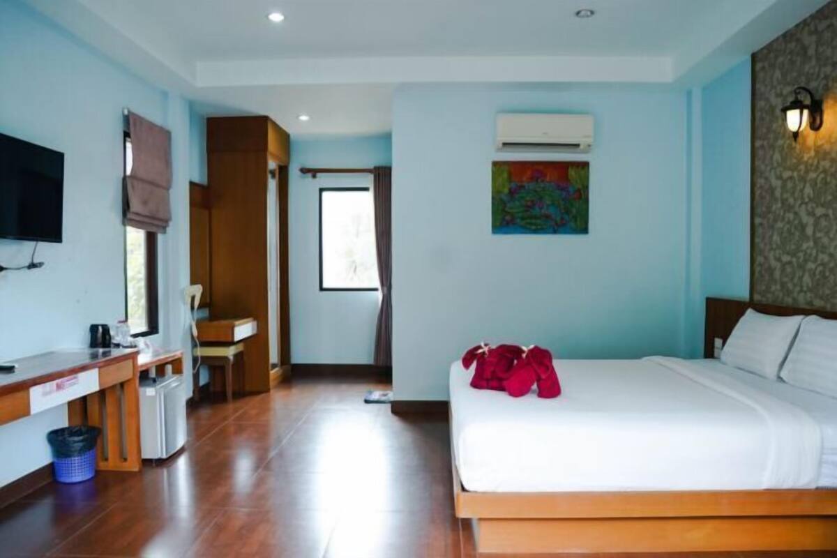 Ein Hotelzimmer mit Bett, Schreibtisch, Sessel, Fernseher und Klimaanlage.