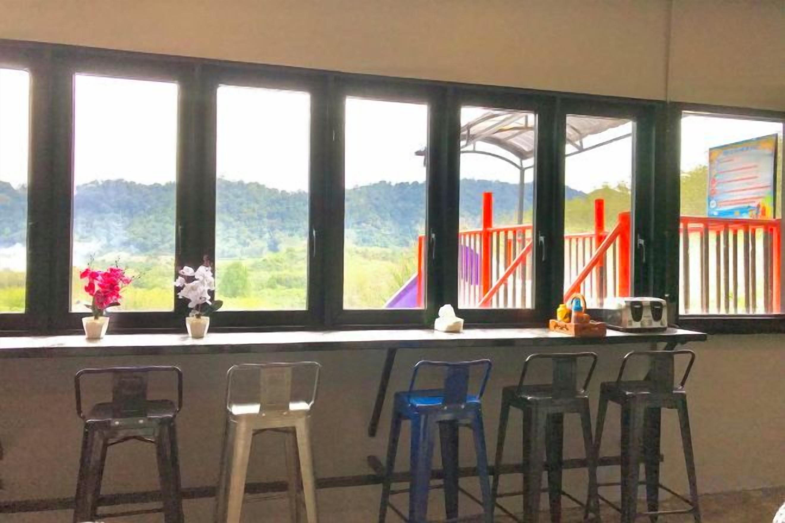 Ein Zimmer mit Blick auf einen Spielplatz und Hügel, ausgestattet mit einem Fenster, vier Stühlen und einem kleinen Tisch.