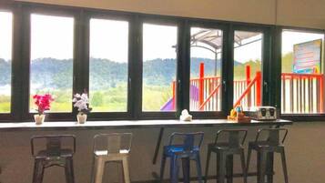 Ein Zimmer mit Blick auf einen Spielplatz und Hügel, ausgestattet mit einem Fenster, vier Stühlen und einem kleinen Tisch.