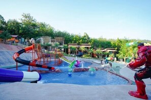 Un parco acquatico con scivoli e piscina, circondato da edifici e alberi.