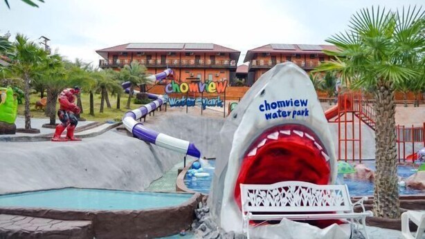 Un parc aquatique doté d’un toboggan aquatique sur le thème des requins et d’un bâtiment portant l’inscription « Chomview Waterpark ».
