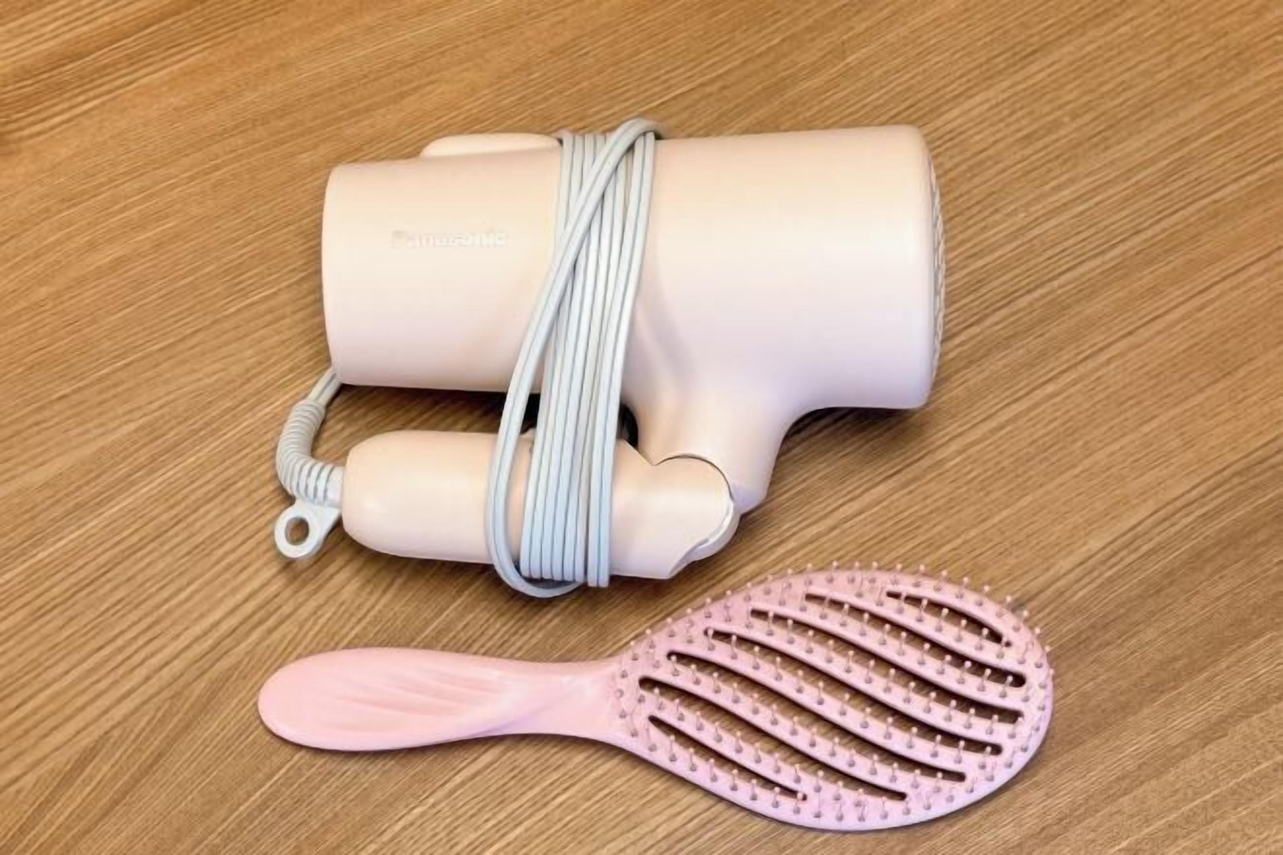 Un sèche-cheveux et un peigne sur une surface en bois.