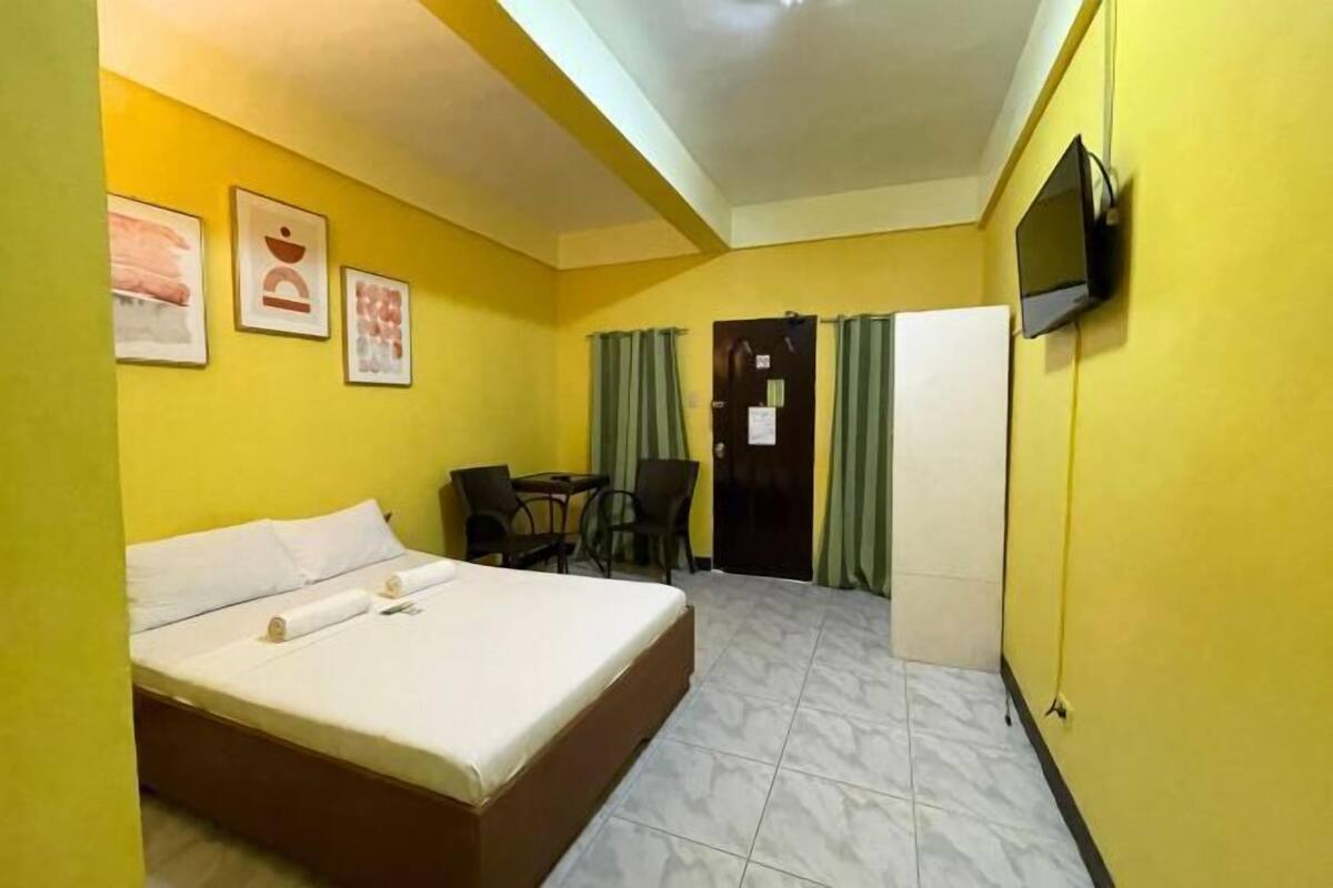 A hotel room with a bed, a TV, a desk, and chairs.