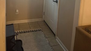 A hallway with a white door, a window with a geometric design, and a patterned rug on the floor. - Cozy 3-bedroom cottage in Hope Mills (Hope Mills)