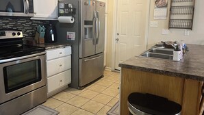 A kitchen with stainless steel appliances, a microwave, oven, refrigerator, and a sink. - Cozy 3-bedroom cottage in Hope Mills (Hope Mills)