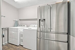 Eine kompakte Küche mit Kühlschrank aus Edelstahl, Waschmaschine und Trockner.