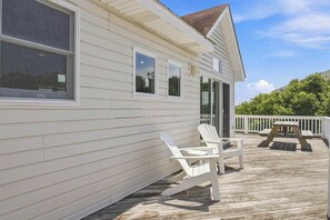 A house with a wooden deck, white exterior siding, and a white railing. - Reality Check | Private Pool and Hot Tub | Sailfish Beach Access (Corolla)