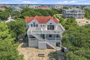 A multi-story house with a red roof, a balcony, and a staircase leading to the upper level. - Reality Check | Private Pool and Hot Tub | Sailfish Beach Access (Corolla)