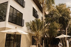 Un edificio con balconi, ombrelloni e palme.