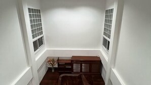 Een kamer met een houten bank, een radiator en een vaas met bloemen.