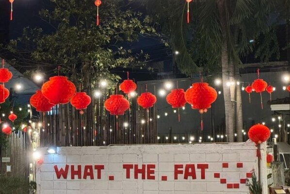 Eine Ziegelwand mit einem Schild, auf dem 'WHAT. THE. FAT.' steht.