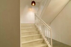 Un escalier avec des rampes blanches et un luminaire au-dessus.